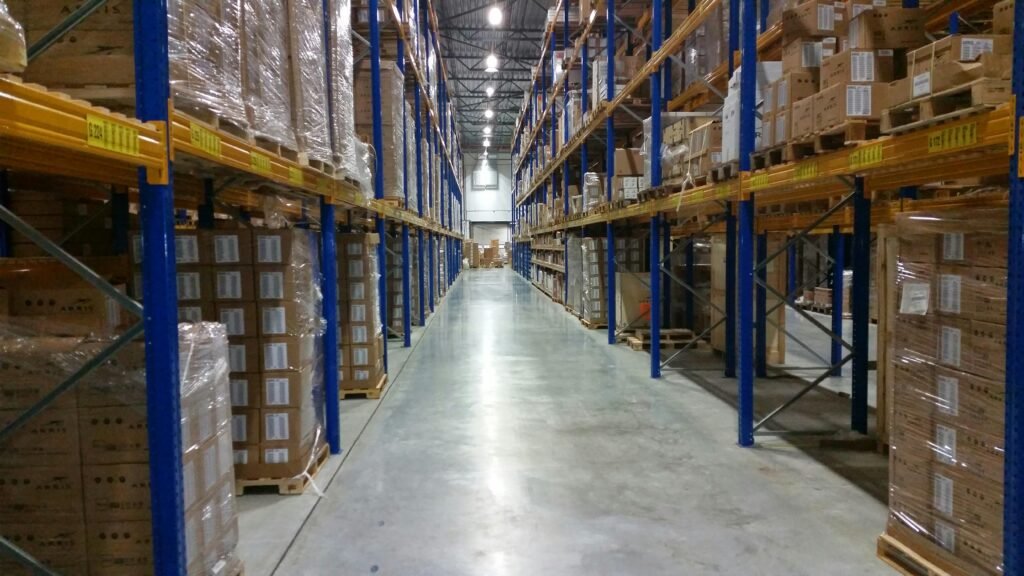 Interior view of a large warehouse aisle lined with stacks of organized cardboard boxes.